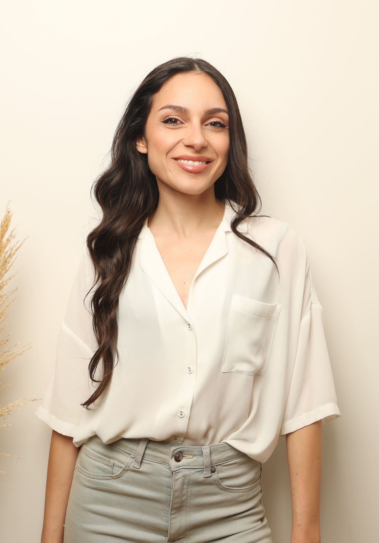 Portrait of Aria smiling in a light blouse against a neutral background