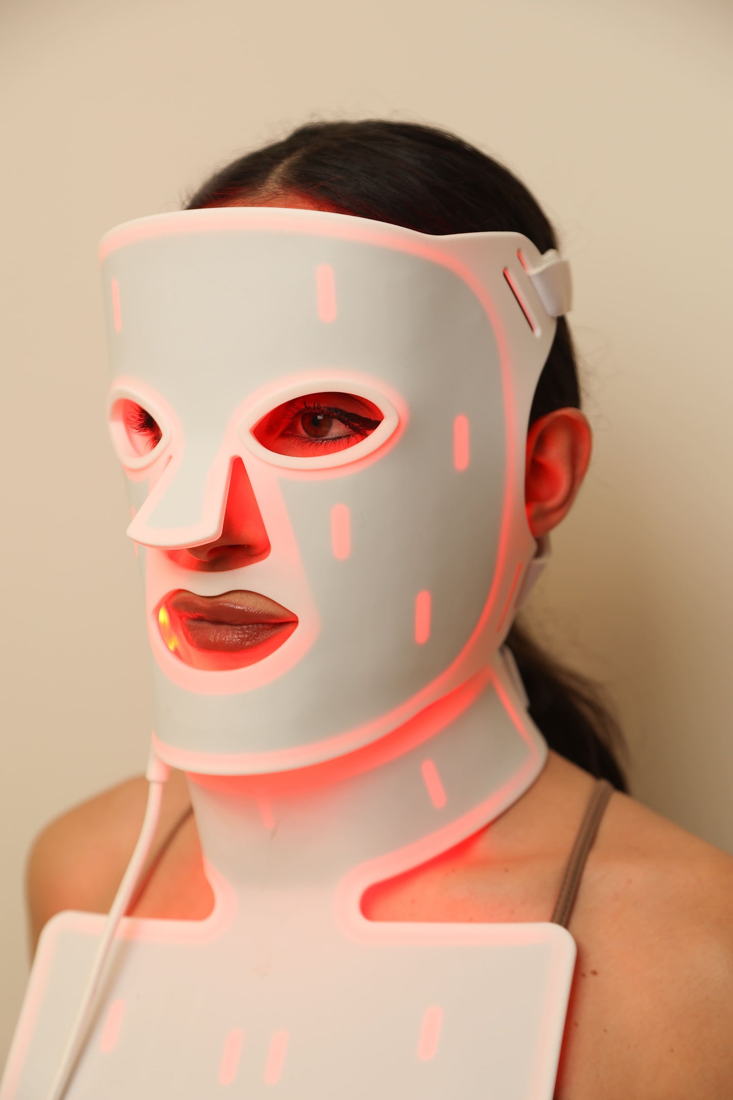 Close-up of woman wearing a red light therapy face and neck mask with red light