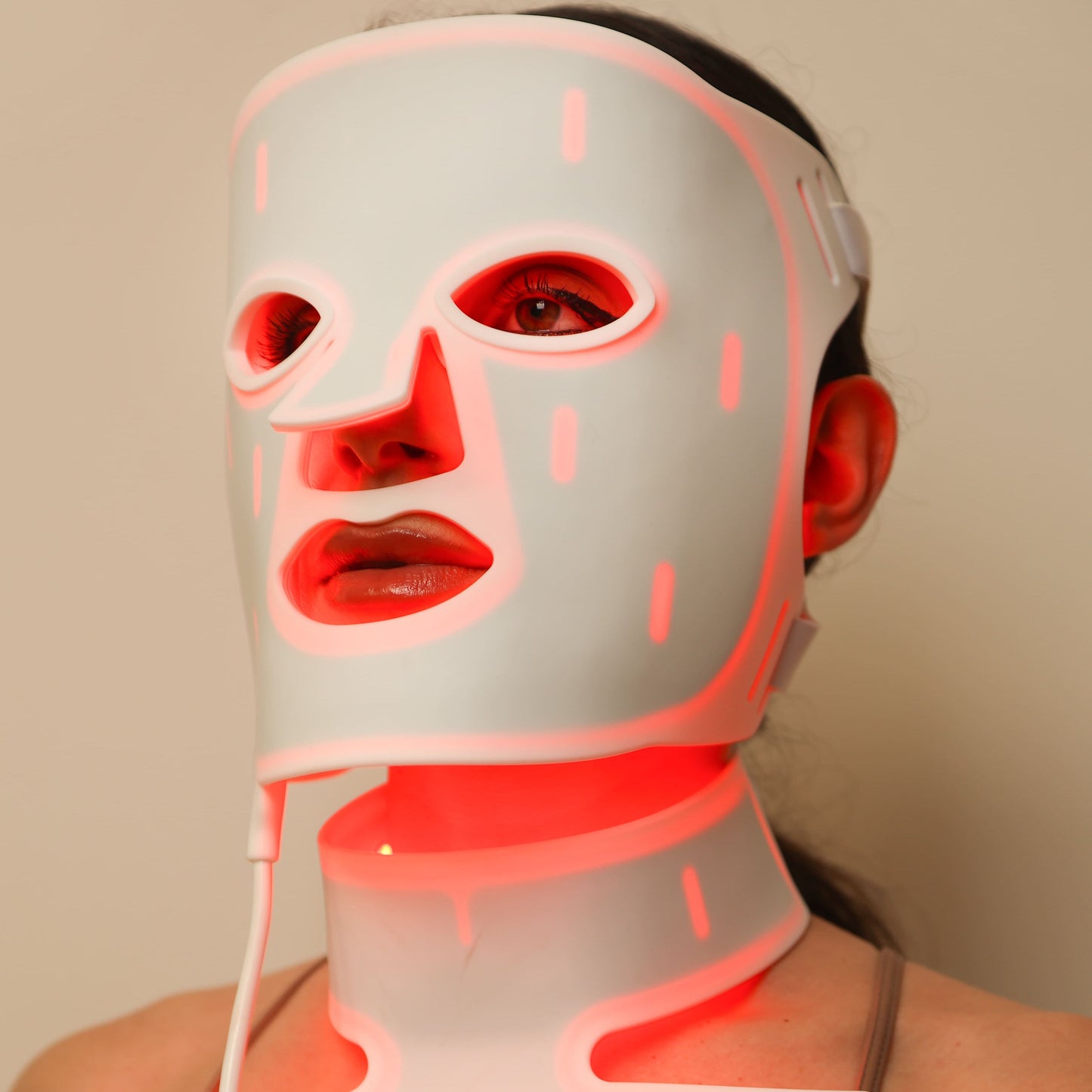 Front close-up of woman wearing a red light therapy face and neck mask during treatment